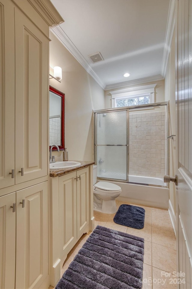 full bathroom featuring vanity, combined bath / shower with glass door, crown molding, tile patterned flooring, and toilet