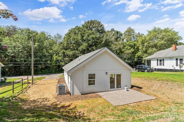 rear view of property with central AC unit, a patio area, and a lawn