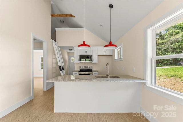 kitchen with light stone counters, a peninsula, stainless steel appliances, white cabinetry, and a sink