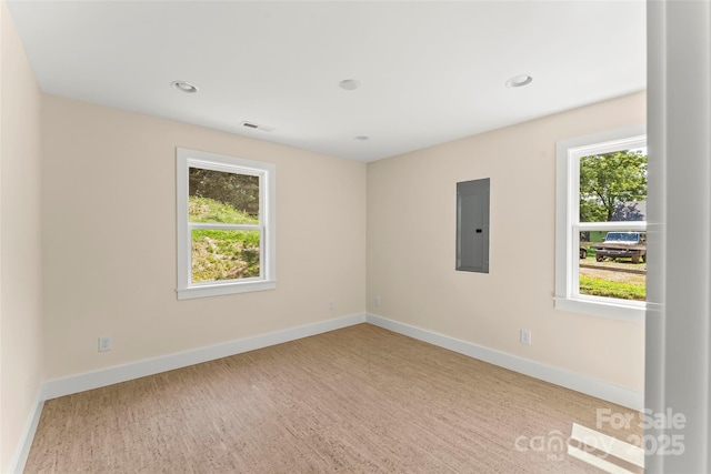 unfurnished room with visible vents, wood finished floors, electric panel, and baseboards