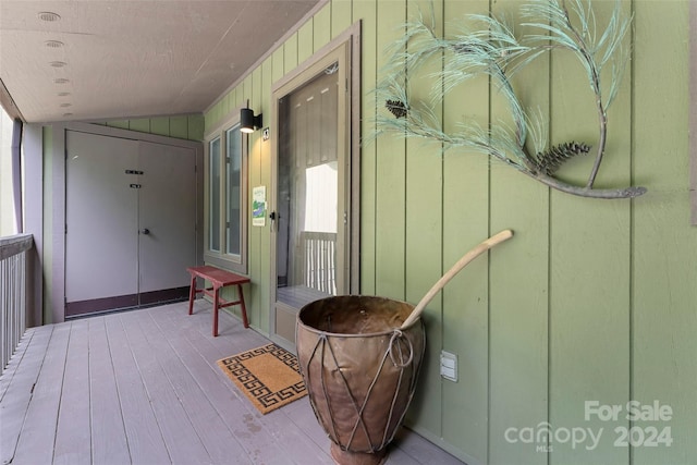 hall featuring light hardwood / wood-style floors, wood walls, and lofted ceiling