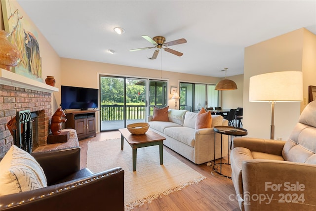 living room with a fireplace, light hardwood / wood-style floors, and ceiling fan