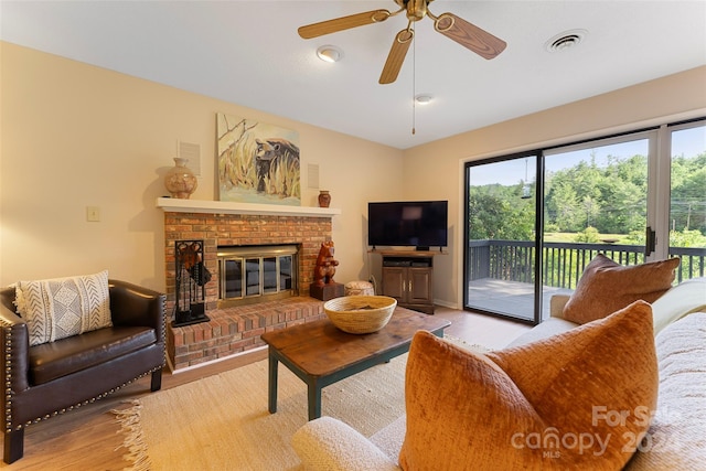 living room featuring a fireplace, ceiling fan, and light hardwood / wood-style flooring