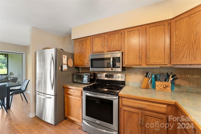 kitchen featuring backsplash, light hardwood / wood-style flooring, and stainless steel appliances