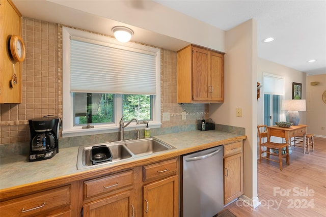 kitchen with dishwasher, light hardwood / wood-style floors, decorative backsplash, and sink