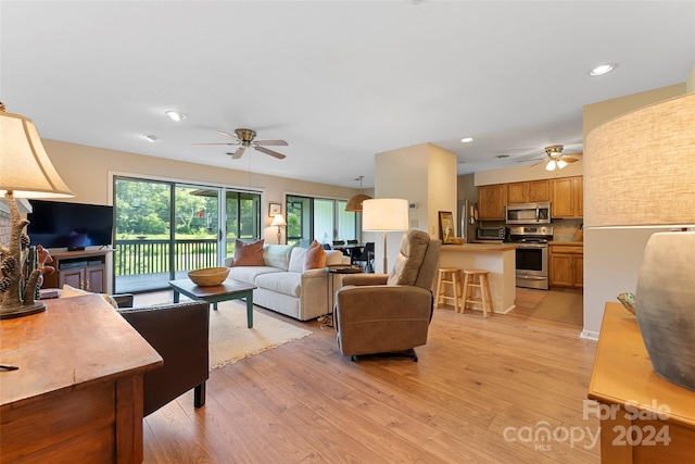 living room with ceiling fan and light hardwood / wood-style flooring