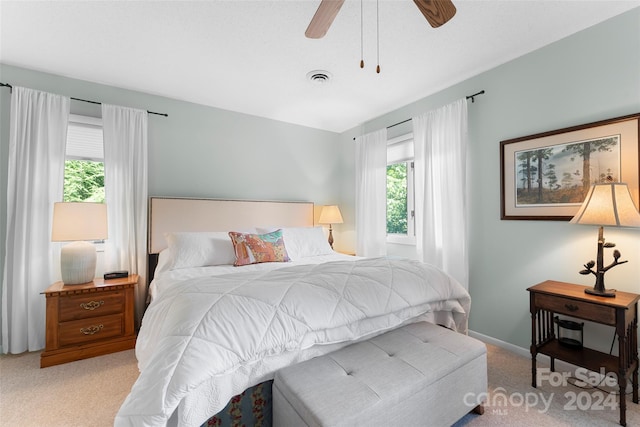 carpeted bedroom featuring multiple windows and ceiling fan