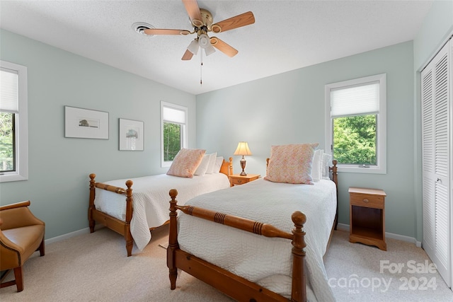 carpeted bedroom featuring ceiling fan and a closet