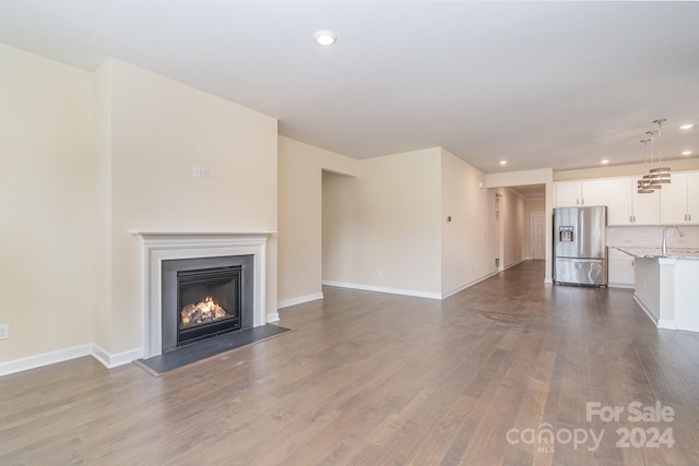 unfurnished living room featuring sink and dark hardwood / wood-style flooring