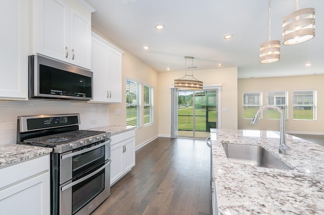 kitchen featuring appliances with stainless steel finishes, pendant lighting, white cabinets, and sink