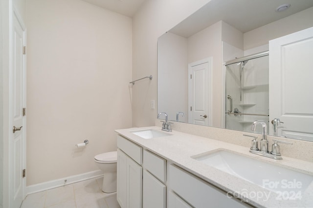 bathroom with an enclosed shower, vanity, toilet, and tile patterned flooring