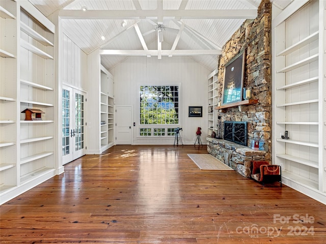 unfurnished living room featuring built in shelves, ceiling fan, wood-type flooring, beamed ceiling, and a fireplace