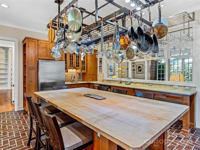 kitchen featuring decorative backsplash, appliances with stainless steel finishes, kitchen peninsula, ornamental molding, and sink