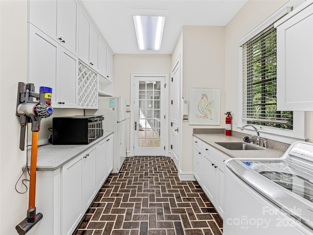 kitchen featuring white refrigerator, washer / clothes dryer, white cabinetry, and sink