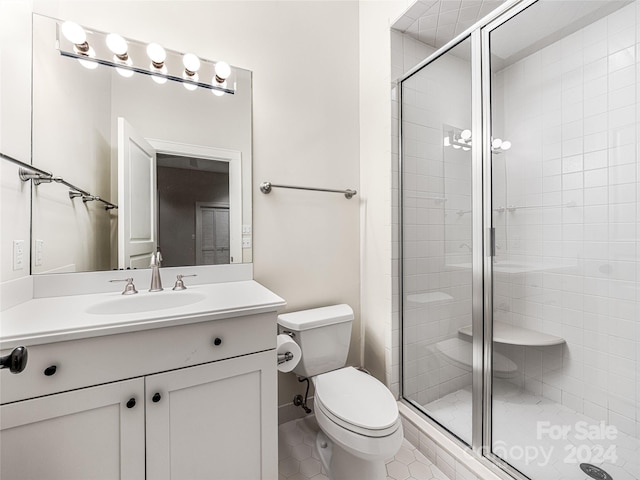 bathroom with toilet, vanity, tile patterned floors, and a shower with shower door