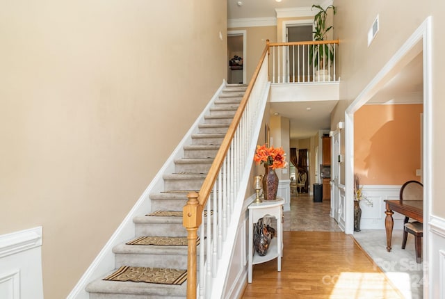 stairway featuring hardwood / wood-style flooring, a high ceiling, and crown molding