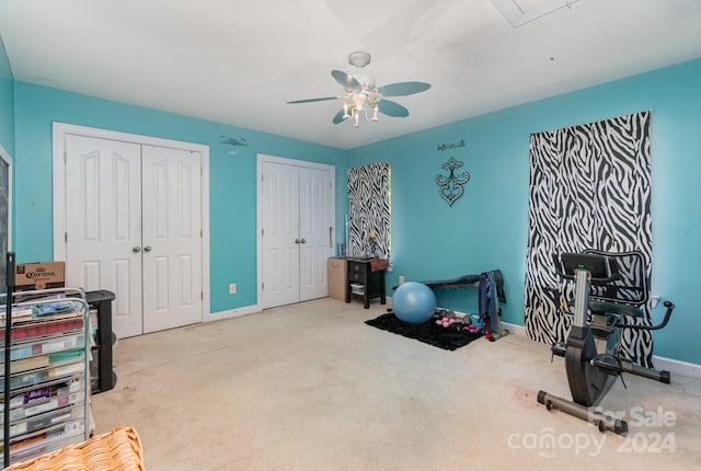 workout room with ceiling fan and light colored carpet