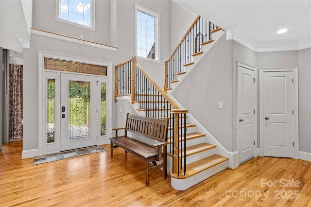 foyer entrance with crown molding and light wood-type flooring