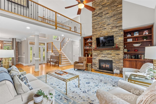 living room with light hardwood / wood-style flooring, built in features, ceiling fan, and a high ceiling