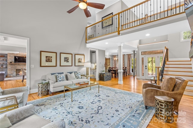 living room featuring a healthy amount of sunlight, decorative columns, ceiling fan, and a high ceiling