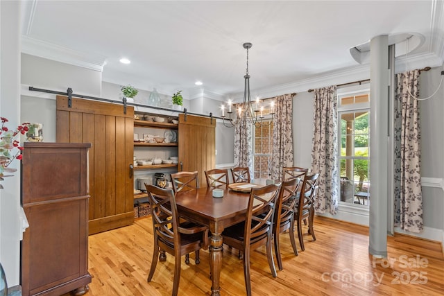 dining room with an inviting chandelier, ornamental molding, light hardwood / wood-style floors, and a barn door