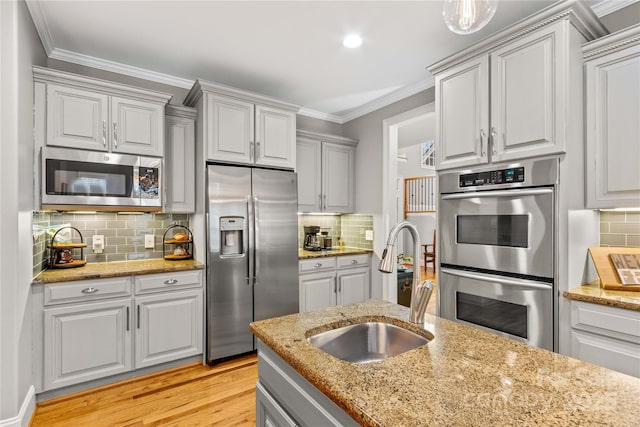 kitchen with tasteful backsplash, sink, stainless steel appliances, crown molding, and light wood-type flooring