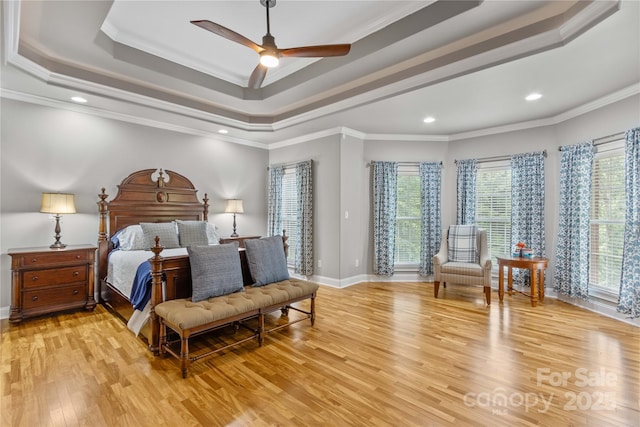 bedroom with crown molding, ceiling fan, a raised ceiling, and light wood-type flooring