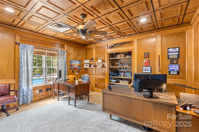 home office with coffered ceiling, ceiling fan, wooden walls, and built in shelves