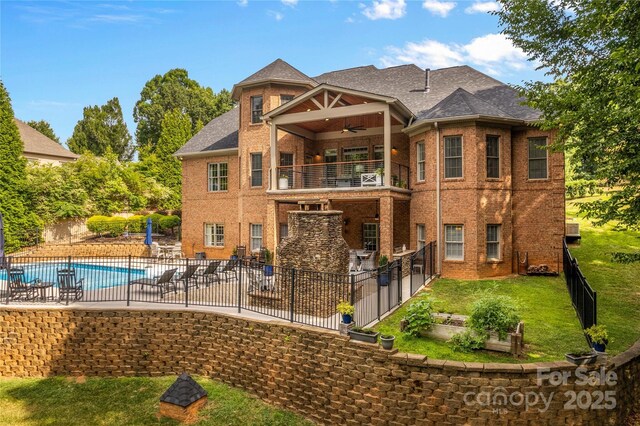 back of property featuring a fenced in pool, a lawn, ceiling fan, a patio, and a balcony