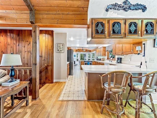 kitchen featuring stainless steel fridge, light hardwood / wood-style floors, kitchen peninsula, a breakfast bar area, and wood ceiling