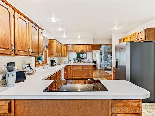 kitchen featuring sink, kitchen peninsula, stainless steel fridge, white dishwasher, and black electric cooktop