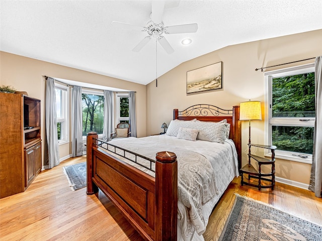 bedroom with ceiling fan, light hardwood / wood-style flooring, and vaulted ceiling