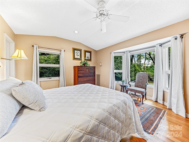 bedroom with hardwood / wood-style floors, a textured ceiling, ceiling fan, and lofted ceiling