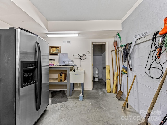 basement featuring stainless steel fridge and sink