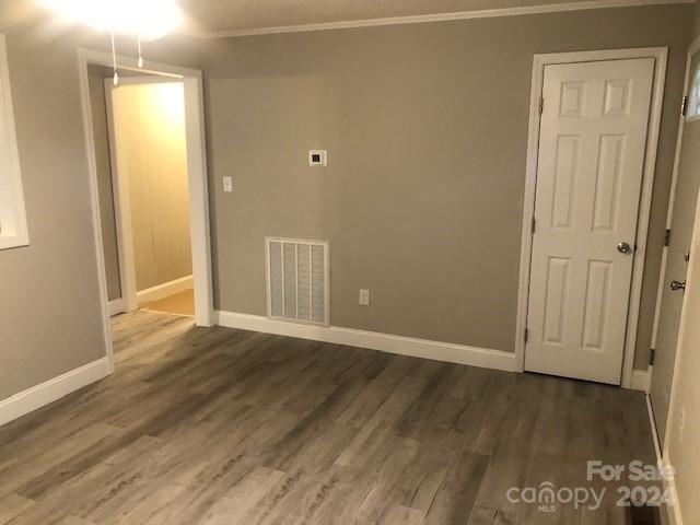 spare room featuring dark wood-type flooring and ornamental molding