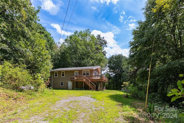 rear view of property with stairway, a yard, and a deck