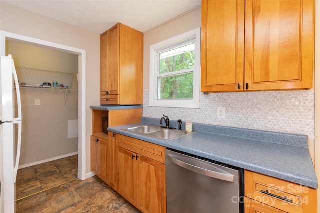 kitchen with a sink, stainless steel dishwasher, freestanding refrigerator, decorative backsplash, and baseboards