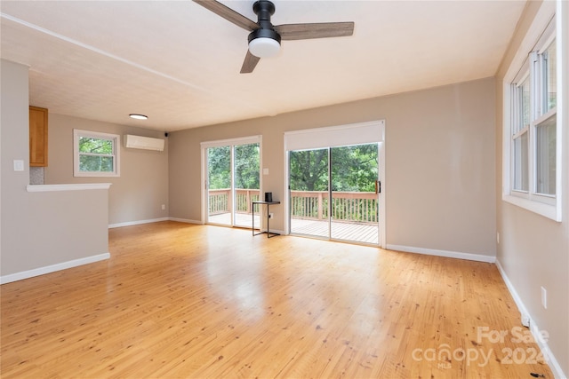 unfurnished room featuring ceiling fan, light hardwood / wood-style floors, and an AC wall unit