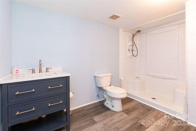 bathroom with wood-type flooring, walk in shower, vanity, and toilet