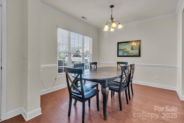 dining room featuring hardwood / wood-style floors, ornamental molding, and an inviting chandelier