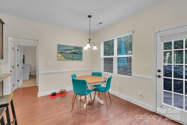 dining space featuring a wealth of natural light, wood-type flooring, and a notable chandelier