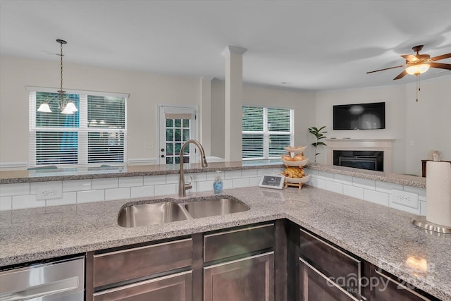 kitchen with dark brown cabinetry, dishwasher, sink, pendant lighting, and ceiling fan with notable chandelier