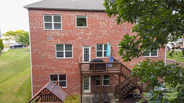 rear view of house featuring a wooden deck and a lawn