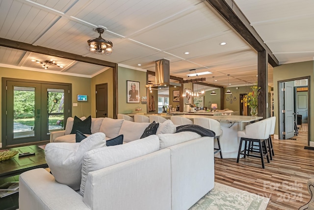 living room featuring light hardwood / wood-style floors, a chandelier, lofted ceiling, and french doors