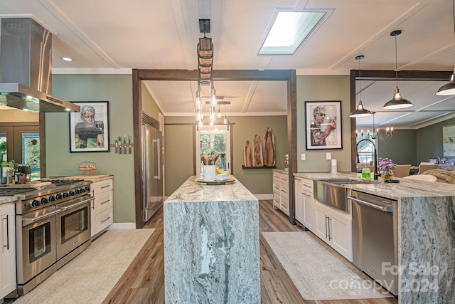 kitchen featuring white cabinetry, an island with sink, island exhaust hood, decorative light fixtures, and high quality appliances