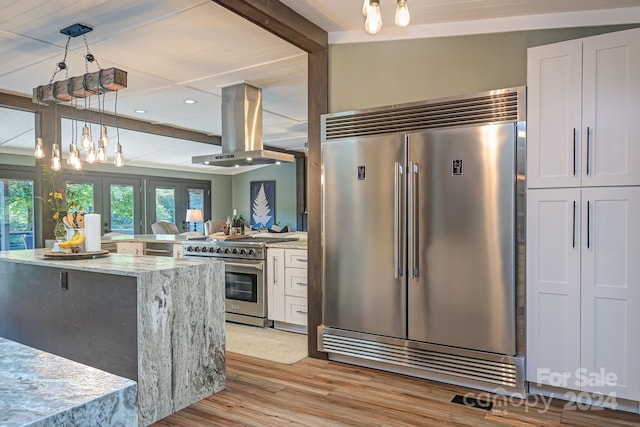 kitchen featuring white cabinets, hanging light fixtures, island range hood, light stone counters, and high quality appliances