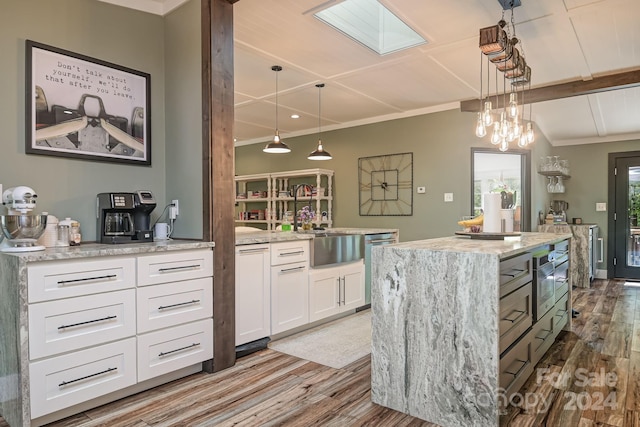 kitchen with pendant lighting, white cabinets, a kitchen island, wood-type flooring, and sink