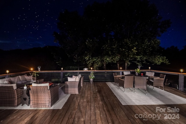 deck at night featuring outdoor lounge area