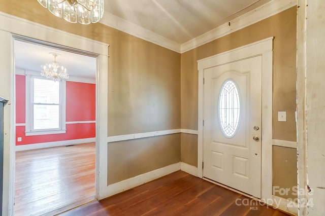 foyer with hardwood / wood-style flooring, a chandelier, and crown molding