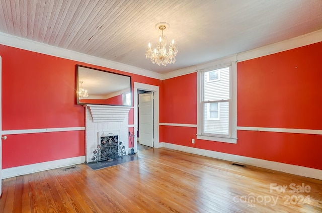 unfurnished living room with hardwood / wood-style flooring, a chandelier, a brick fireplace, and wood ceiling